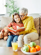 © Lumos sp - grandchild family child grandparent grandmother book reading elderly granddaughter girl  happy together read learning education woman