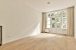 an empty living room with wood flooring and large windows in the room is very clean, but it's all white
