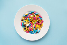 Colorful Pills In A Large White Bowl On A Blue Background. The Concept Of Health And Evidence-based Medicine. Place For An Inscription.
