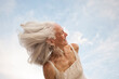 Happy senior woman portrait  with her hair dancing in the wind. 