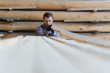 Wall Mural - Timber harvesting for construction. Carpenter stacks boards. Industrial background. Authentic workflow