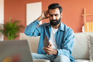 Wall Mural - Middle Eastern Guy At Laptop Looking At Empty Wallet Indoor