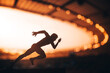 Chasing Glory: Silhouette of an Athlete, Primed for Speed, Standing Tall Amidst the Luminous Dusk at a Modern Sports Stadium. Warm sunset light. Edit space for your montage, games 2024 in Paris