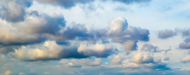Wall Mural - Blue sky with big puffy colorful clouds at sunrise or sunset shot at 54 mm focal length