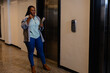 Plus size african american casual businesswoman talking on smartphone in office corridor
