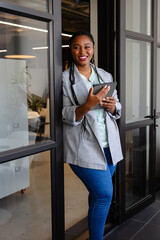 Happy plus size african american casual businesswoman using tablet in office window