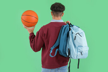 Poster - Male student with ball and backpacks on green background, back view