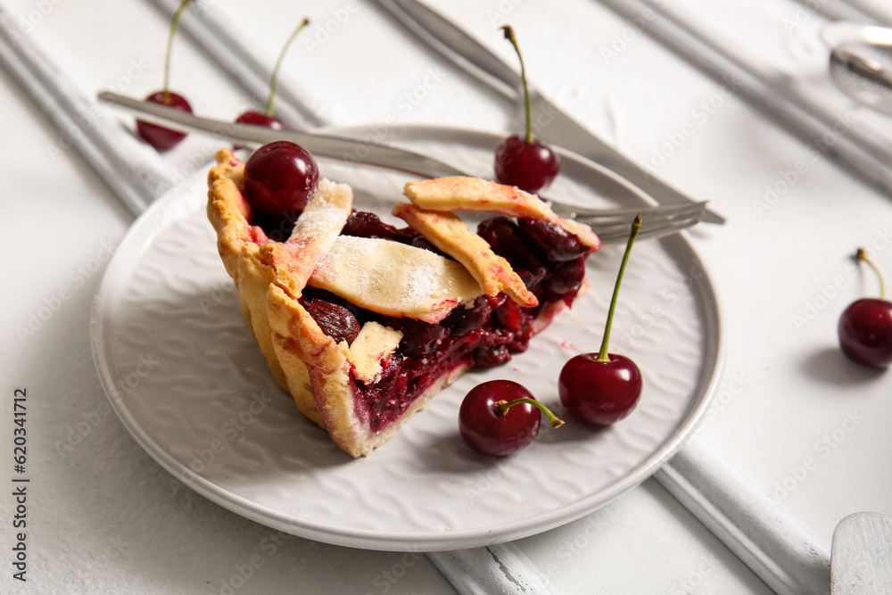 Plate with piece of tasty cherry pie on white background