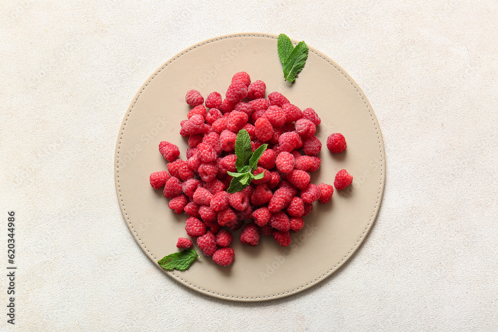 Heap of fresh raspberries and mint on white background