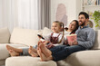 © New Africa - Happy family watching TV with popcorn on sofa at home