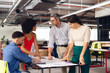© Wavebreak Media - Diverse casual business people looking at architectural plans and discussing work at office