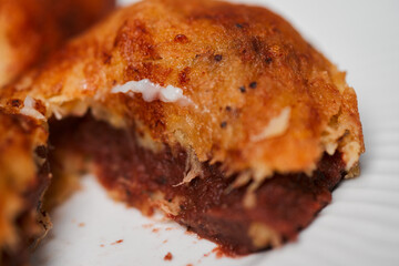 Close up photo of empanadas dessert from El Salvador central america made of bean paste sliced in two on wooden block and white dish