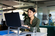© Wavebreak Media - Happy asian casual businesswoman at desk in office using laptop on stand, smiling