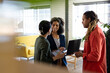 © Wavebreak Media - Three happy diverse casual business colleagues with tablet and laptop standing in office talking
