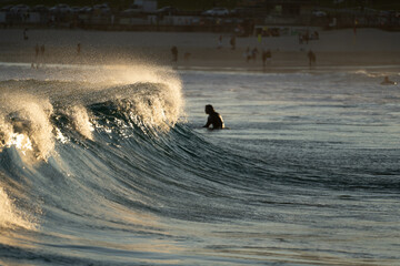 Wall Mural - Waves breaking sunset reflection silhouette surfers