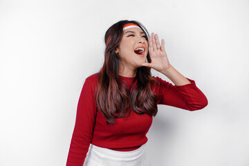 young beautiful woman wearing a red top shouting and screaming loud with a hand on her mouth. indone