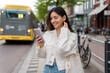 © Andrei - Happy commute on public transport. Multi-ethnic attractive woman with beautiful smile at bus station looking at phone