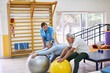 © Robert Kneschke - Physiotherapist guiding elderly patient exercising with fitness ball