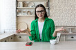 © Liubomir - Worried young woman sitting in the kitchen at home and looking disappointed at the camera. Raises hands.