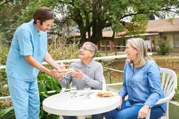 Wall Mural - Caregiver with senior people having meal in garden of nursing home