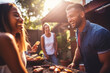 © Denis Yevtekhov - A multiethnic group of friends gathered around a barbecue, grilling and enjoying a sunny day in the backyard Generative AI
