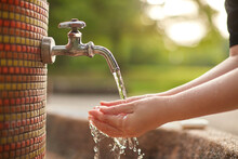 庭の水道水の蛇口で手洗いしている女性の両手の様子