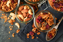 Homemade Granola In Glass Jar With Greek Yogurt Or Milk And Cashews, Almonds, Pumpkin With Dried Cranberry Seeds In Dark Grey Table Background. Healthy Energy Breakfast Or Snack. Top View
