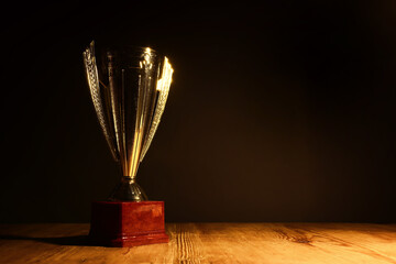 Wall Mural - low key image of trophy over wooden table and dark background