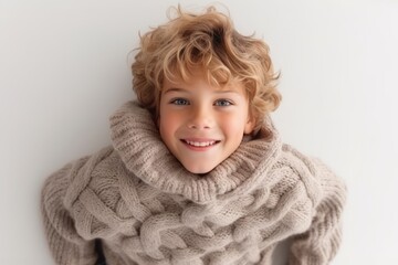 Poster - Portrait of a cute blond boy in a warm sweater on a white background