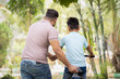 © WESTOCK - rear view tracking shot of indian father teaching cycling or bike riding to his son at park - concept of Joyful Guidance, Childhood Memories and Parental Support