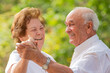 © carballo - smiling senior couple dancing happily outdoors