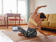© EASY 2 SHOOT/Stocksy - Relaxed woman doing yoga stretching at home