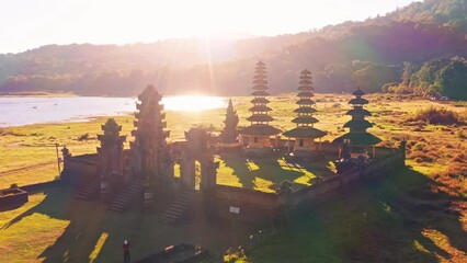 Wall Mural - Beautiful Bali temple in the rays of the rising sun against the background foggy mountain landscape Bali, Indonesia 4K Aerial view