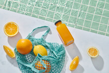 Ripe Orange And Lemon In A String Bag And Bottle Of Fresh Citrus