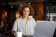 © Jovo Jovanovic/Stocksy - Portrait of entrepreneur smiling with laptop in cafe