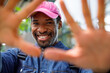 © Jovo Jovanovic/Stocksy - Happy bearded man wearing cap with backpack showing palm of hands