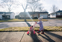 Toddler Walks Down Sidewalk Pushing Doll Stroller