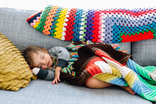 Little girl sleeps with knit blankets on couch
