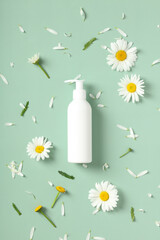 Wall Mural - empty white cosmetic bottle with pump and daisy flowers on green background. spa beauty product desi
