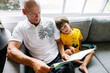 © Maria Manco/Stocksy - Grandpa reads book to grandson