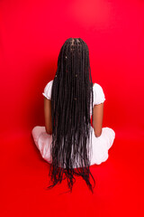 Wall Mural - Young black woman, sitting with her back to the camera showing her hair braids.