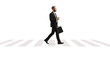 © Ljupco Smokovski - Full length profile shot of a businessman walking with a briefcase and a takeaway coffee at a pedestrian crossing