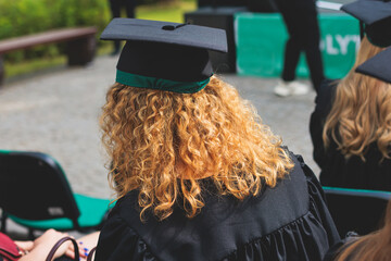 Graduation ceremony in university, female students wearing black mantles and academic mortarboard cap, group class of high school graduates receive diploma and getting college degree