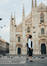 Tourist Woman Exploring Milan's Duomo At Sunrise Around Flying Pigeons