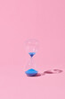 © Marc Tran/Stocksy - Hourglass with blue sand on pink background.