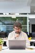 © Santi Nuñez/Stocksy - Senior man using laptop in office