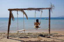 A Woman Swinging On A Swing By The Sea