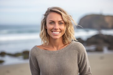 Portrait of a smiling young woman standing on the beach at sunset