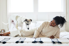 Mature Black Woman Playing With Her Pet Dog In Bedroom At Home