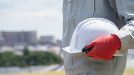 ヘルメットを持つ作業服の男性｜建設業・製造業などのイメージ